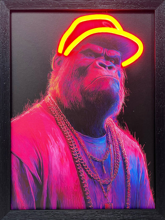 Framed mixed media wall art depicting a stylized gorilla in a pink jacket and heavy gold chains, holding a microphone. The gorilla wears a backward baseball cap defined by a glowing, functional yellow LED neon outline, making this street-art-inspired piece a true statement item