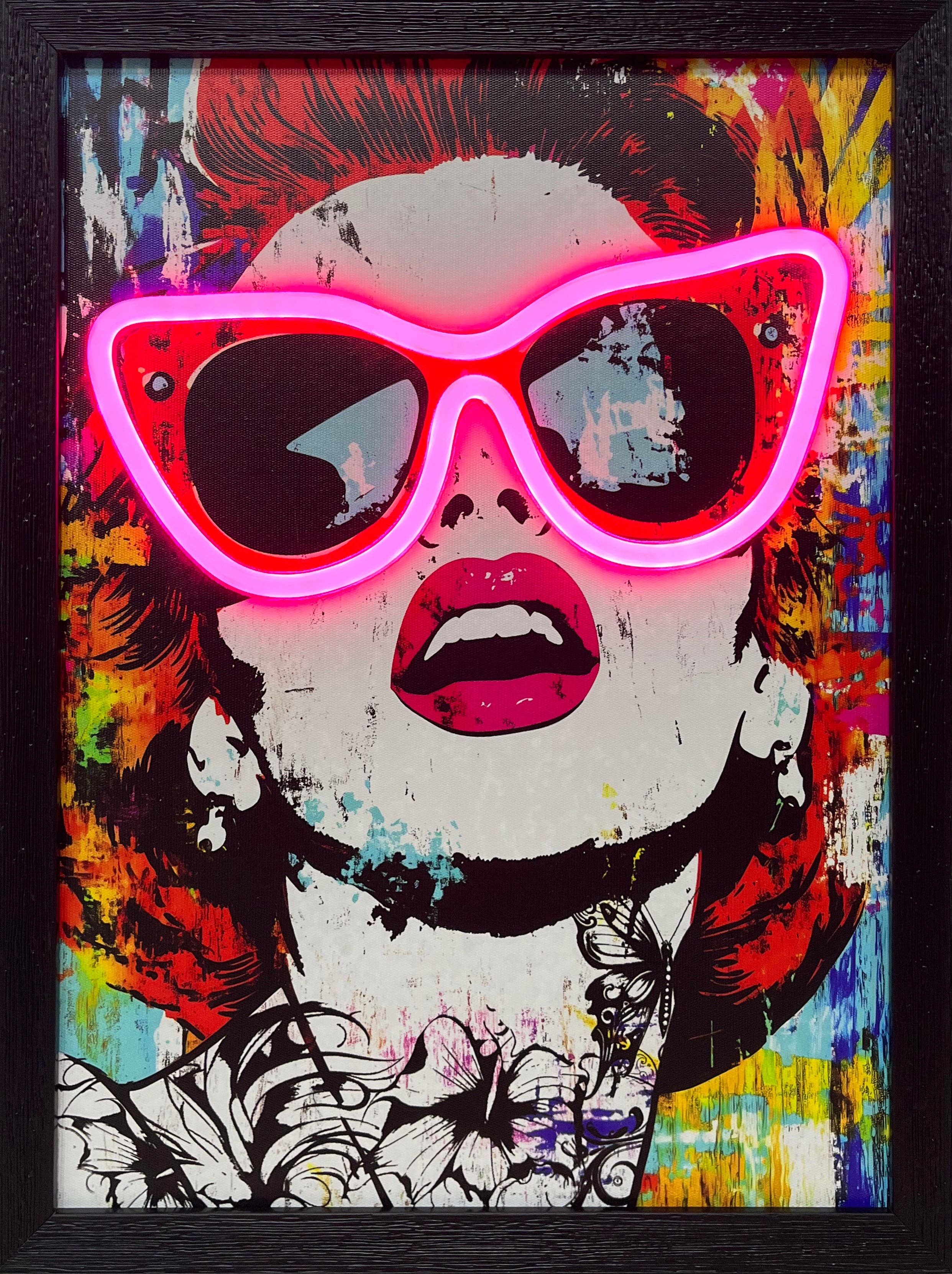 A vibrant, framed pop art portrait of a woman with graphic, floral neck tattoos and bold pink lips. Her exaggerated cat-eye sunglasses are outlined by a bright, functional pink LED neon light, creating an electric focal point on the colorful, abstract splatter background.